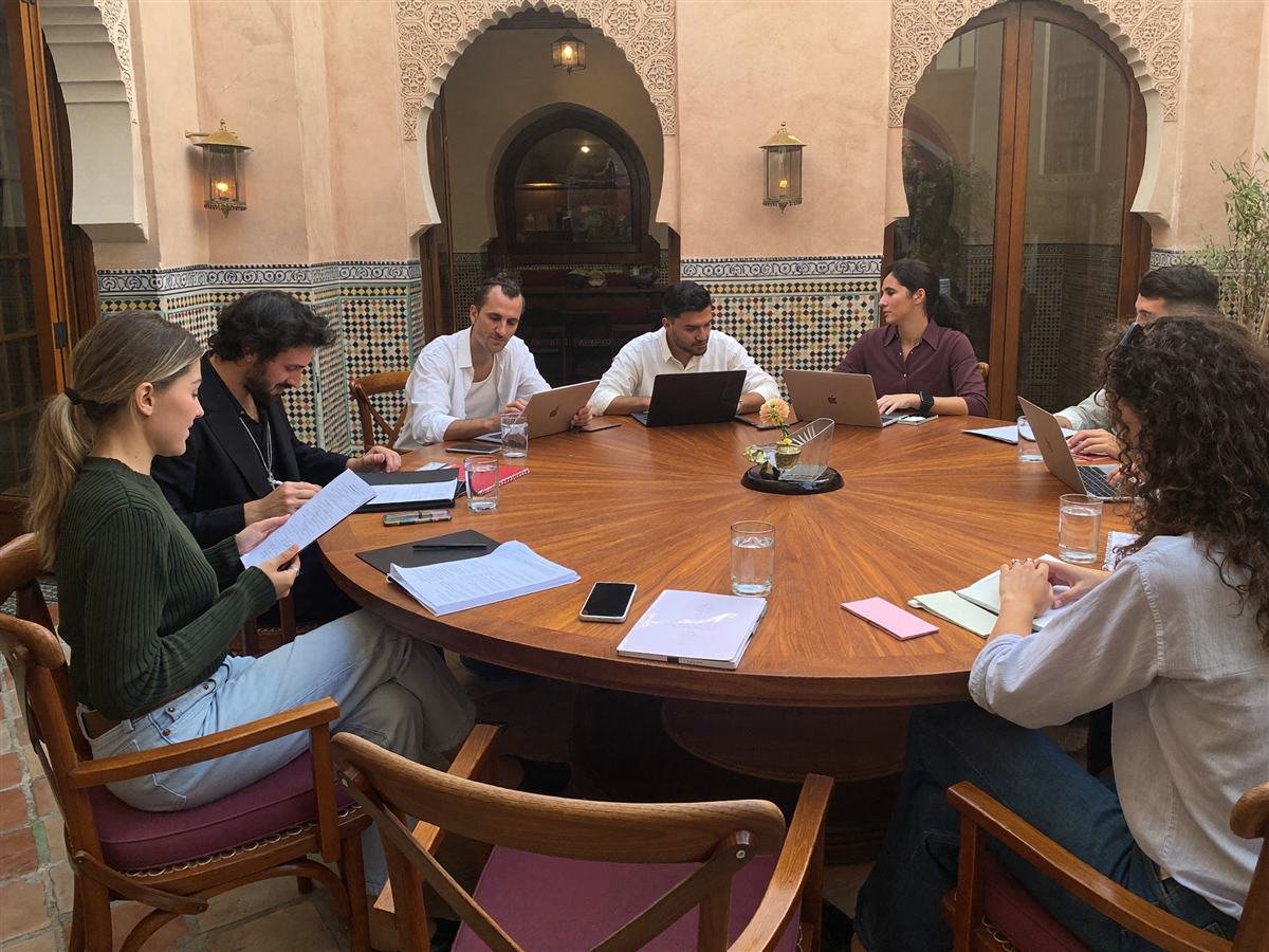 Table de 8 entrepreneurs en session de travail dans le patio d'un riad