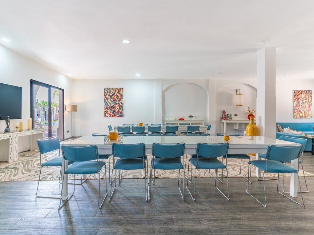La salle de travail de la villa, avec une grande table et des chaises bleues