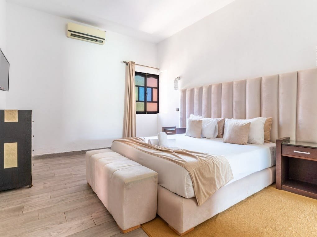 Une suite de la villa, avec un grand lit et une tête de lit capitonnée